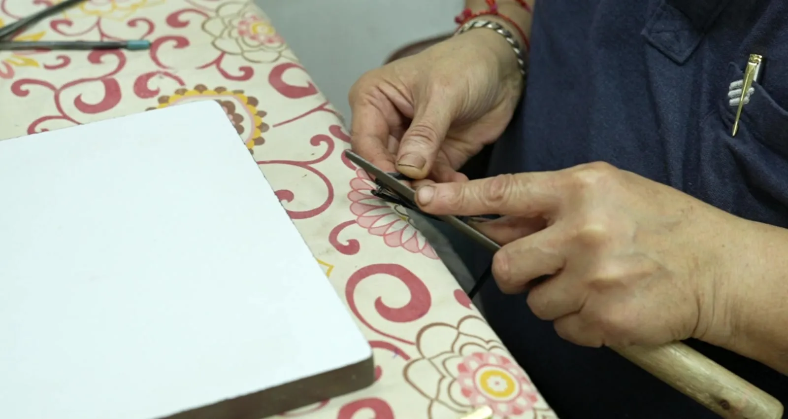 Hands working a frame front against a sample card at the development bench
