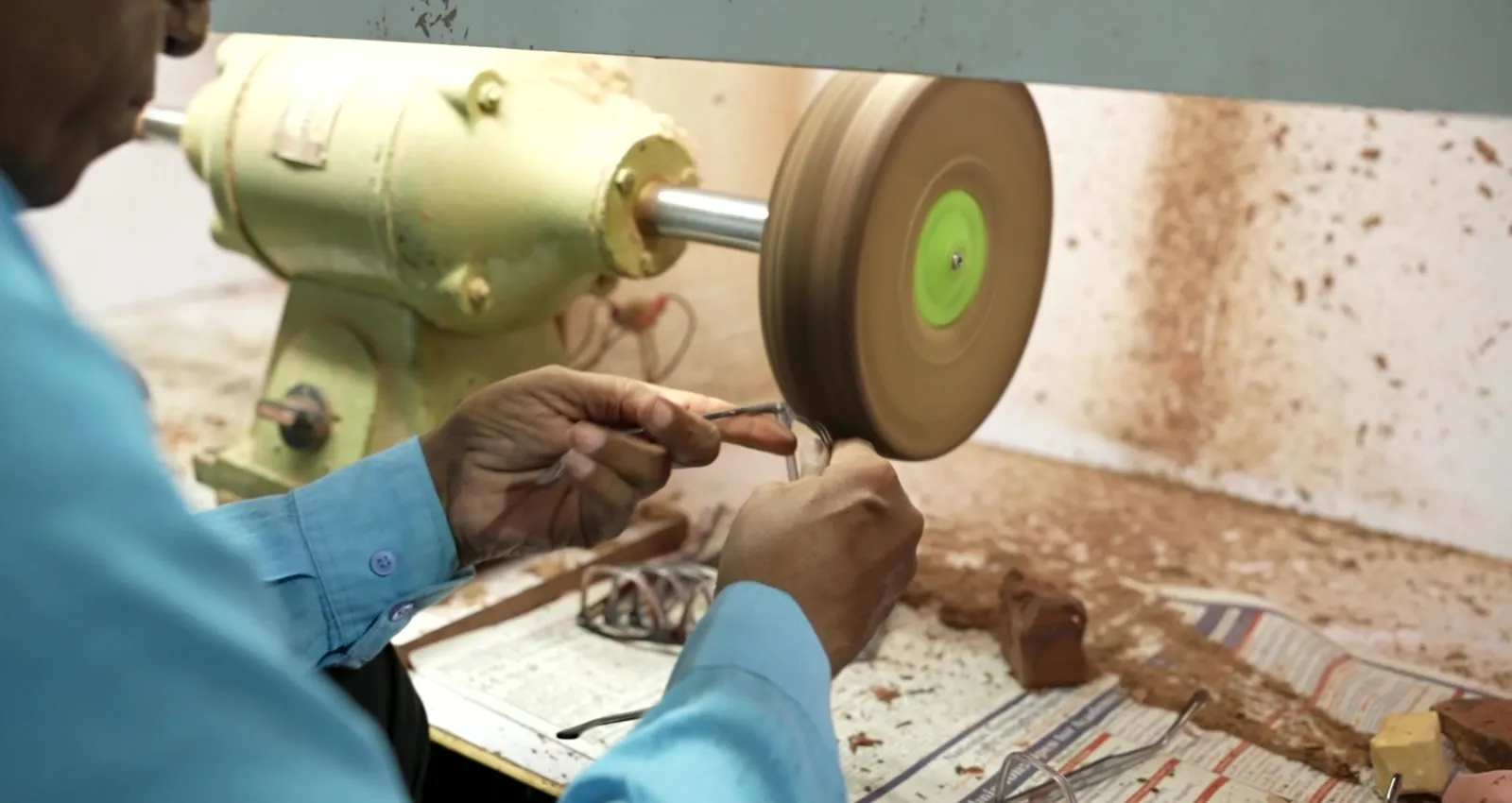 A craftsman finishing an acetate frame at the polishing wheel
